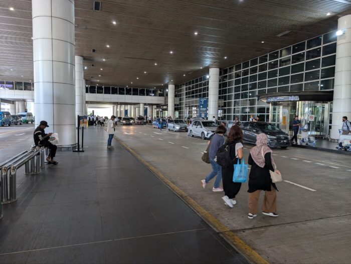 右手が空港2番出口、左手にあるオレンジの看板が三井アウトレットパーククアラルンプール行きシャトルバス乗り場案内
